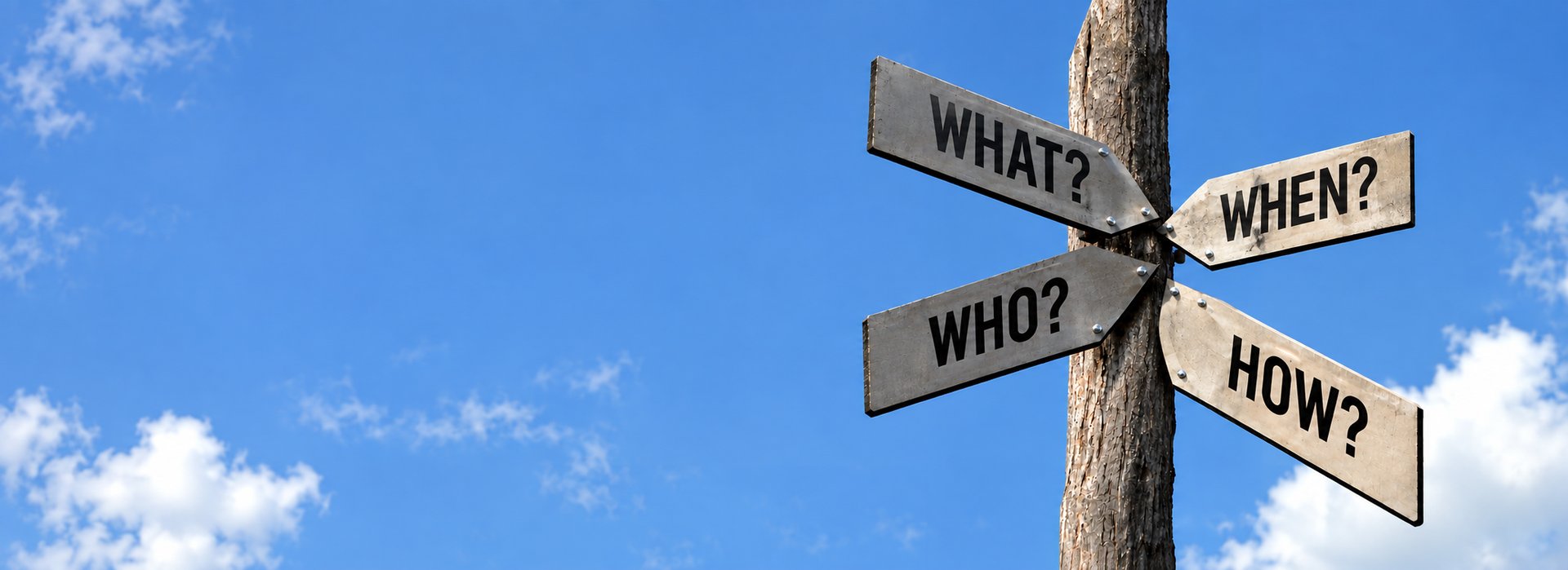 Wooden signpost against a blue sky with clouds, showing directional signs reading "What?", "When?", "Who?" and "How?", symbolizing guidance and decision support
